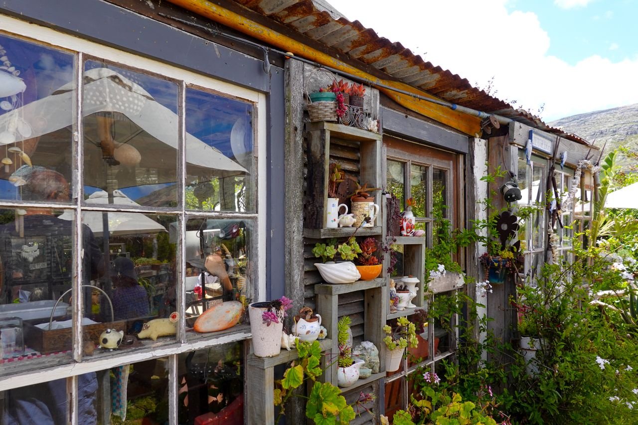 A rustic shed with artistic garden decor and potted plants creating a charming outdoor setting.