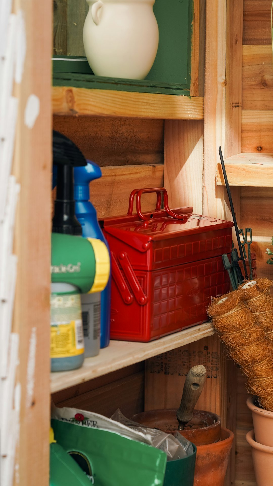 gardening-tools-and-a-red-toolbox-on-wooden-shed-shelves-fn7pf14w10g