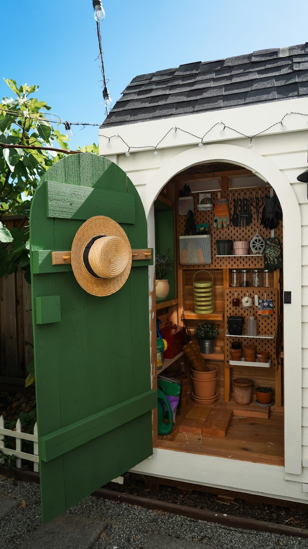 open-white-garden-shed-with-green-door-and-gardening-supplies-s399fgcqn-s